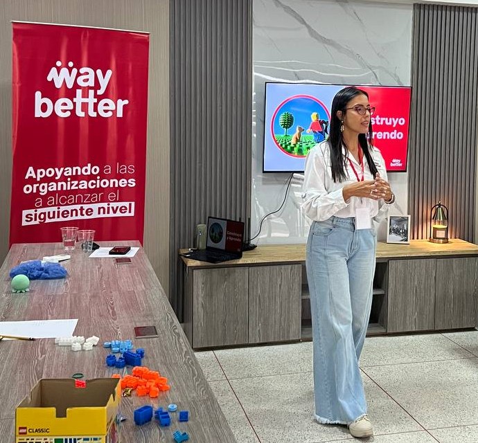 Facilitadora de WayBetter dictando un taller de formación junto al pendón de WayBetter
